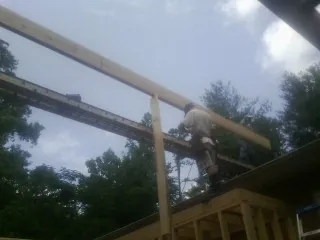 Carpenter setting a ridge beam over a new addition frame — Ice Dam Removal by Roofing Brothers in Mackay