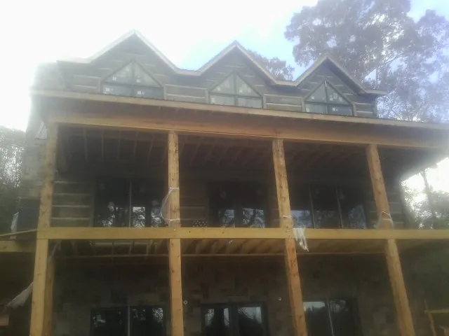 Dormers and porch framing on a large log home under construction — Roof Coating work by our crew in Mackay