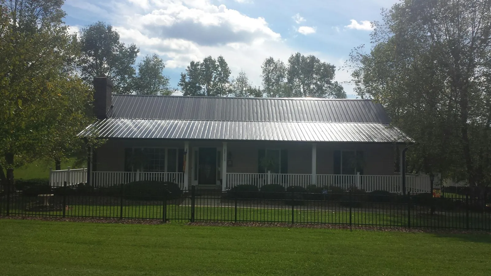Gray metal roof on a brick ranch with a full width front porch — Gutter Guard Installation work by our crew in Mackay
