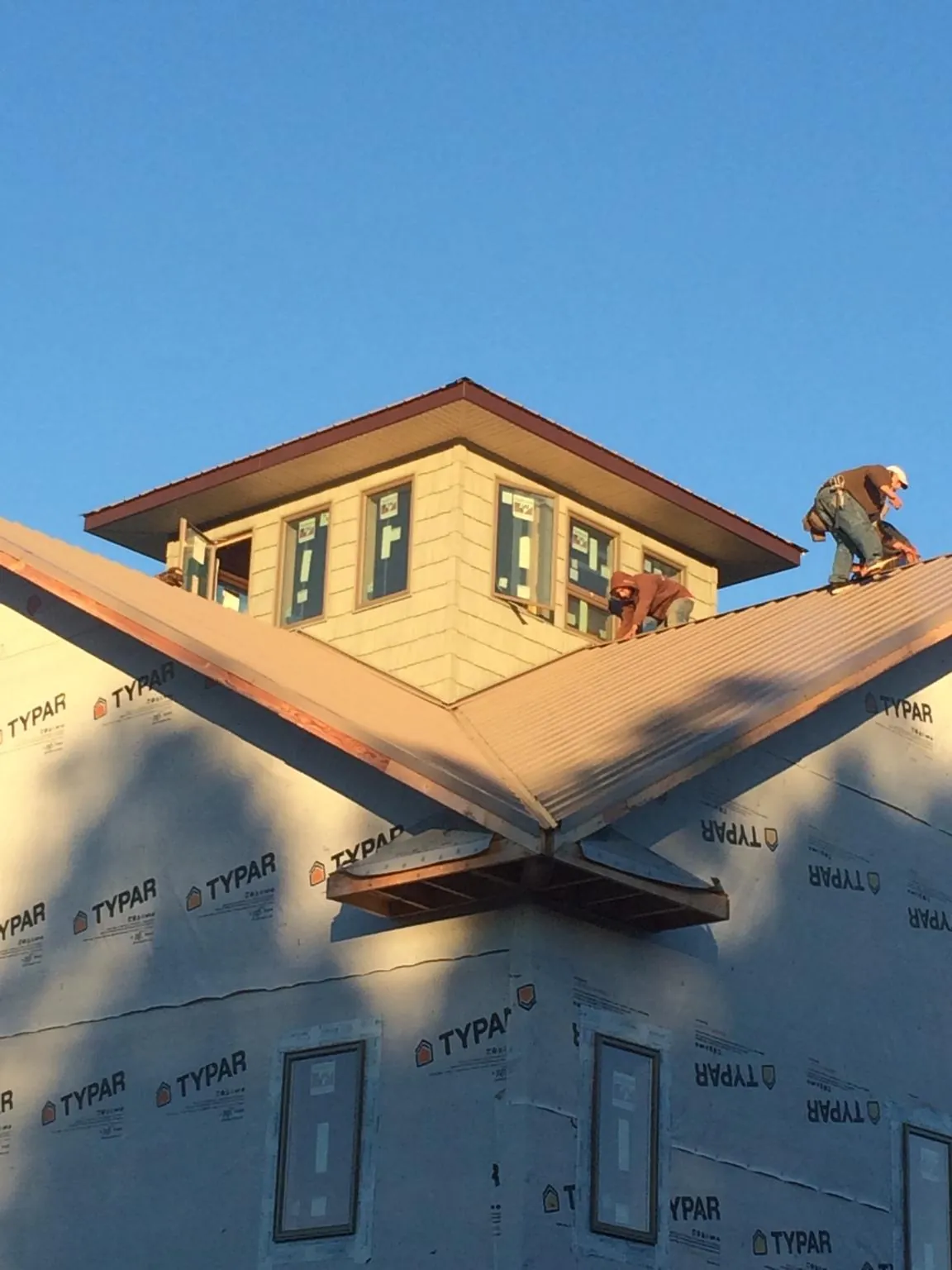 Roofers working around a rooftop cupola on a new metal roof at sunset — Roof Waterproofing in Mackay by Roofing Brothers